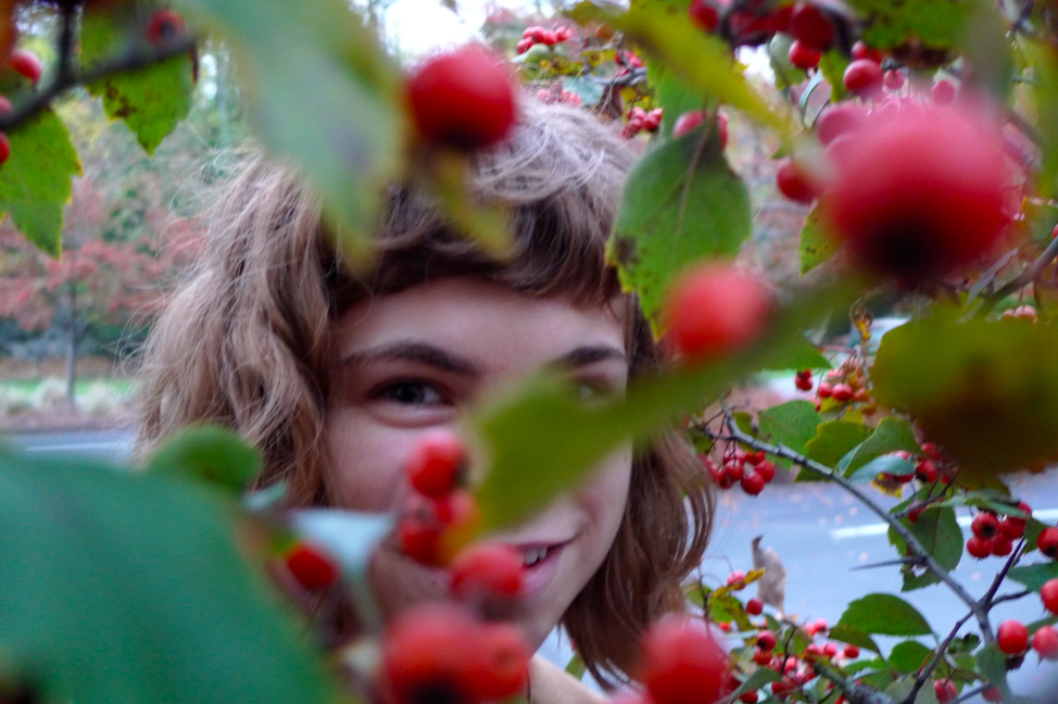 My mom took this photo of me partially obscured behind a tree with red berries... 